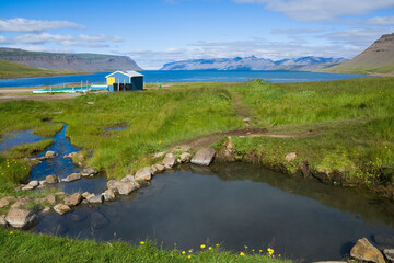 Fototapeta premium Outdoor geothermal pool against the backdrop of mountains and water in Westfjords, Iceland