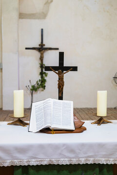 A church altar with a cross, candles, flowers, and an open bible