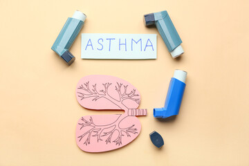 Inhalers, paper lungs and paper sheet with text ASTHMA on beige background