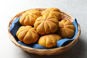 Wicker basket with tasty pumpkin shaped buns on light table, closeup