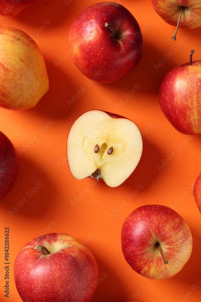 Poster Whole and cut fresh red apples on orange background, flat lay