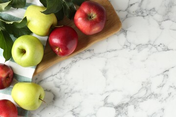 Ripe apples and green leaves on white marble table, top view. Space for text