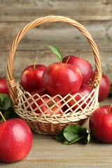 Fresh ripe red apples in wicker basket on wooden table