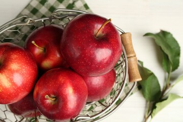 Fresh ripe red apples in basket on white table, closeup