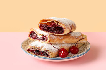 Plate with sweet cherry strudel on colorful background