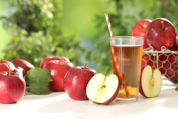 Tasty apple juice in glass and fresh fruits on white table outdoors