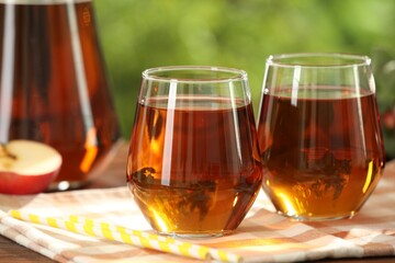 Tasty freshly made apple juice in glasses on table outdoors, closeup
