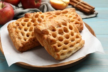 Delicious puff pastries with fruit filling on light blue wooden table, closeup
