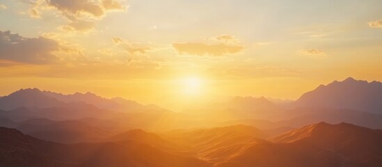 Fototapeta premium A warm sunset casts a golden glow over a mountain range, creating a serene and peaceful landscape.