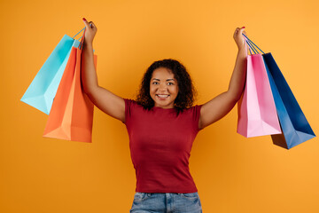 Shopping. Excited African Shopaholic Woman Holding Colorful Shopper Bags On yellow Studio...