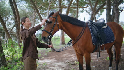 Fototapeta premium Cute cowgirl cleaning pet greenery forest zoom on. Woman rubbing animal muzzle