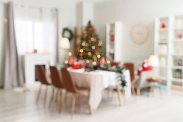 Dining table with setting for Christmas celebration in festive room. Blurred view