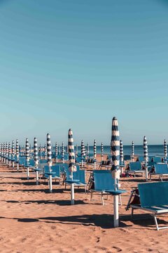 Typical Italian Adriatic Riviera beach near Fano and Marotta, Marche. Rows of blue sunbeds and umbrellas. Vintage vacation atmosphere.