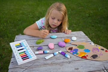 Child craft activities, girl paints heart on stones. Preschooler art work. Mother's day handmade...