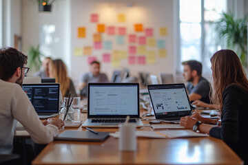 Team collaboration in an open workspace with laptops and post-it notes in a modern office setting during the daytime