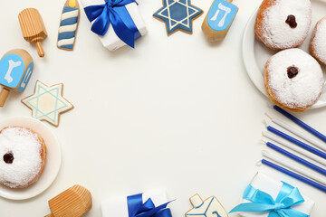 Frame made from donuts, gift boxes, dreidels and candles on light background. Hanukkah celebration