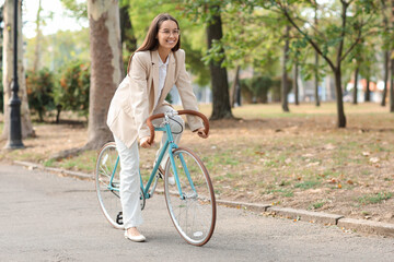 Young businesswoman riding bicycle in city park