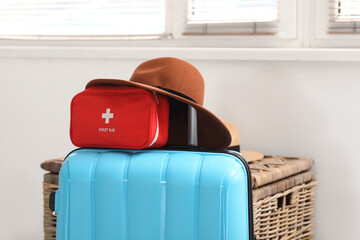 Suitcase with first aid kit and brown hat in room