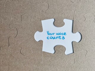 Motivational message 'your voice counts' on a missing puzzle piece with cardboard background
