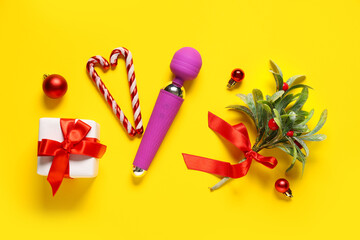 Composition with vibrator, Christmas decorations, mistletoe and gift on yellow background