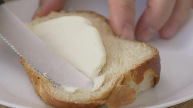 Spreading butter on a wheat slice of bread close-up