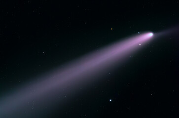 Fototapeta premium The comet traveling through space, with a long, bright tail extending outward. The tail is colored in a striking purple or pinkish hue.