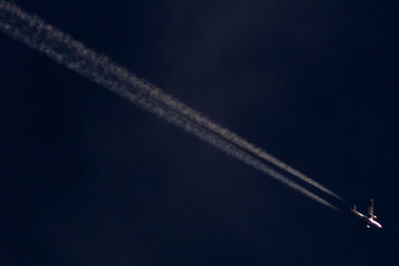 Airplane in the blue sky with white clouds and contrail.