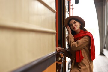 Woman with suitcase getting into train at railway station