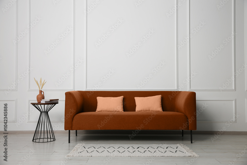 Poster Comfortable brown sofa and table near white wall in room