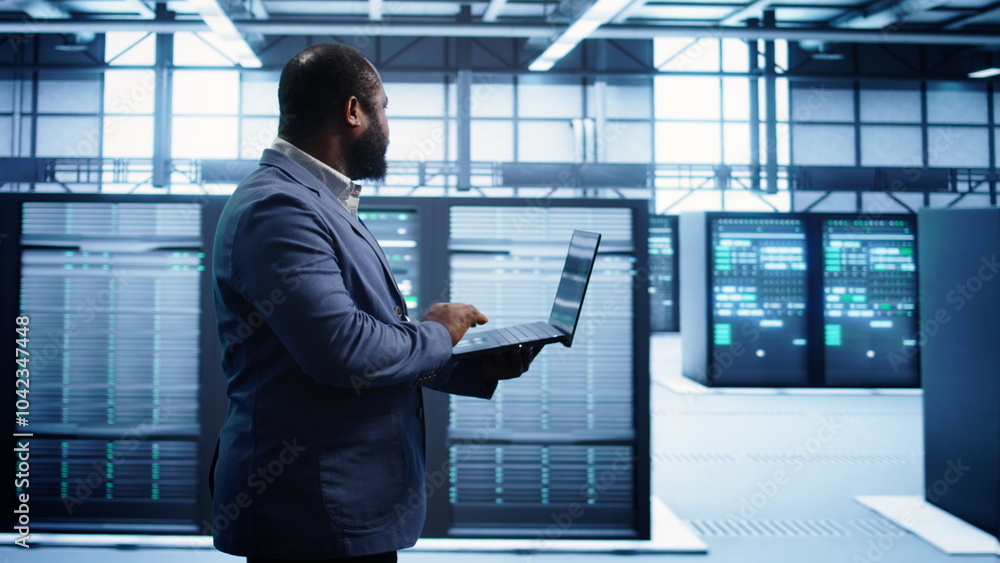 Poster african american man walking in high tech facility, using laptop to patch network issues leading to 