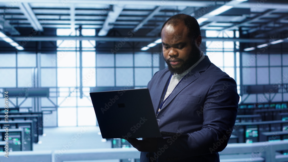 Poster african american it operator doing maintenance using laptop to prolong data center equipment life sp