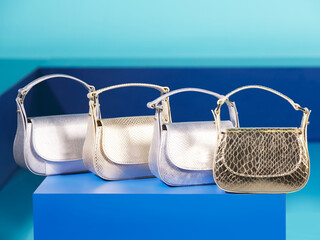 Shiny and stylish leather women's bags with silver and gold look. In the studio, luxury and rich mini bags lined up side by side on the decorative background. New fashion products