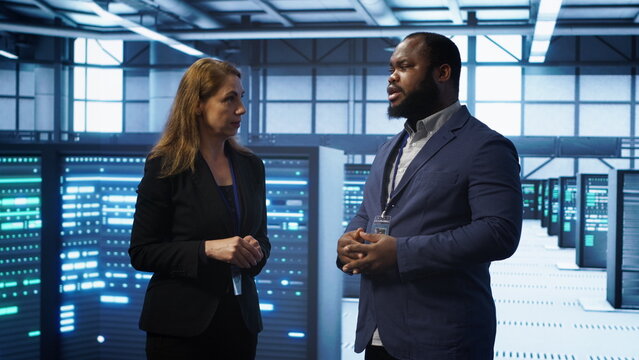 African american expert and coworker looking at holograms in data center, working together. Team members interacting with augmented reality AI visualization in server hub, camera A - Powered by Adobe