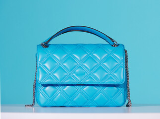 Bright blue patent leather bag. Expensive, quilted patterned, luxury women's bag, on a white ground and turquoise background, studio shot.