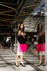 Picky customer is choosing new clothes to buy. Elegant lady is looking for sales in the mall. Window shopping. Young woman is looking for new bargains on Black Friday.