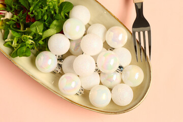 Plate with beautiful Christmas balls and salad on color background, closeup
