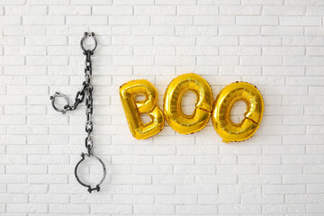 Text BOO made of balloons and shackles hanging on light brick wall