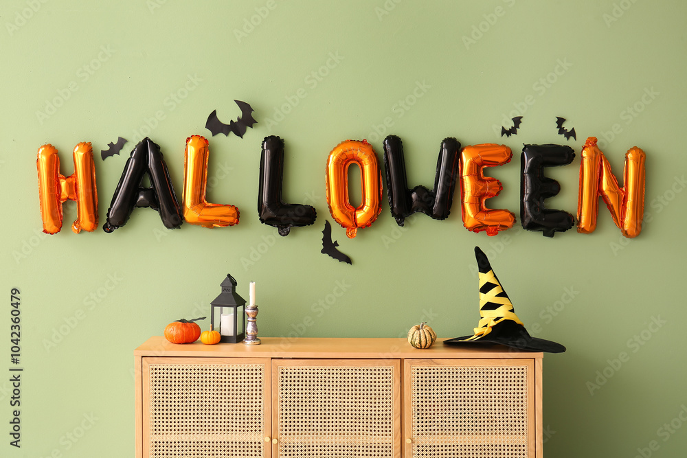 Wall mural Word HALLOWEEN made of balloons with paper bats on green wall in room