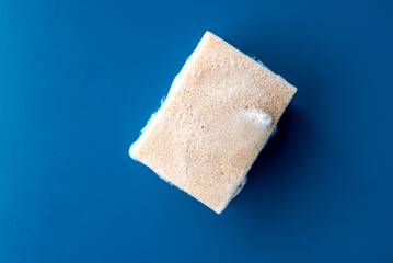 foam sponge for washing dishes on blue ceramic table, copy space.