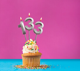 Lit birthday candle with the number 133 - Celebration card on violet and blue background