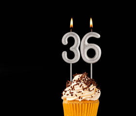 Birthday cupcake on black background - Number 36 shaped candles.