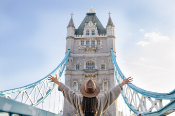 Young beautiful tourist girl is happy and excited to see Tower bridge in London, she is wearing a...