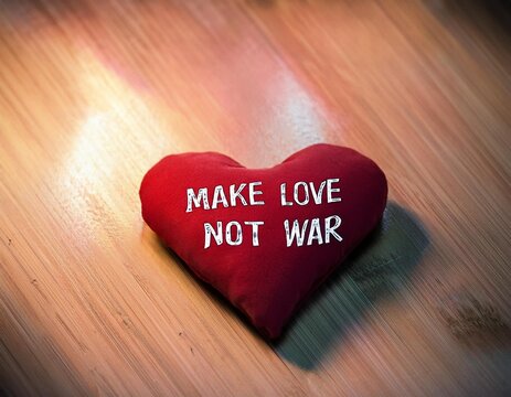 Auf einem hellen Holztisch liegt ein rotes Herzkissen, darauf steht: MAKE LOVE NOT WAR