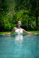 Fototapeta premium A woman relishing a calm moment, swimming in a private pool, surrounded by tranquility and luxury.