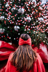 Woman in a red sweater and a red bow in her hair is looking at the Christmas tree in Covent garden in London