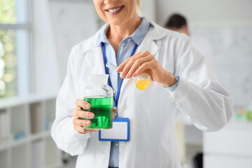 Fototapeta premium Mature female chemist with flasks in laboratory, closeup