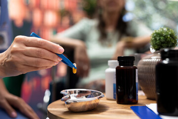 Professional nurse separating pills and medicine in two different bottles, preparing the weekly treatment with daily doses for senior man and woman. Caretaker offer health aid to patients. Close up.