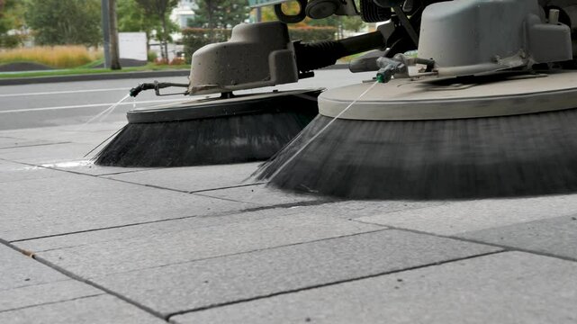 city sweeper cleans the sidewalk from dust by spraying water in front of the rotating brushes. Sweeping asphalt and sidewalks using street cleaning equipment. Cleaning the city from dust