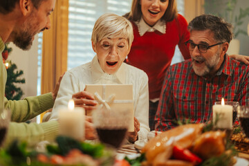 Family having christmas dinner surprising grandmother with a gift