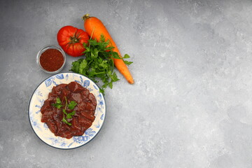 Cut raw beef liver with onions, spices, chili peppers and dill on wooden table, flat lay